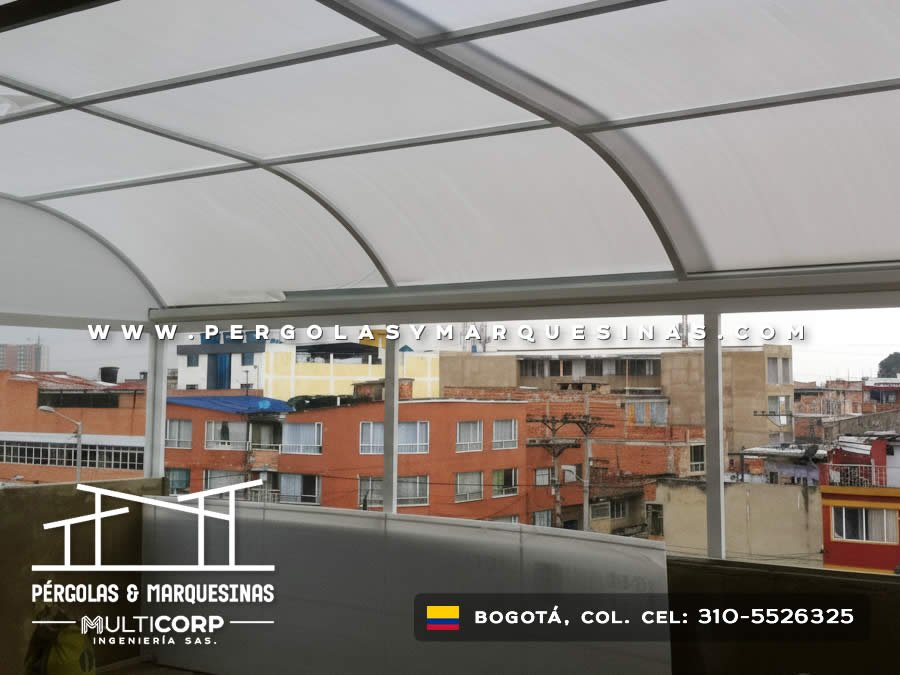 Cubierta en policarbonato curva para balcón con vista urbana panorámica en edificio de Bogotá, Colombia. Multicorp Ingeniería SAS.