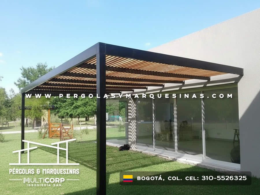 Pérgola bioclimática metálica negra con lamas orientables de madera para terraza con césped en finca en Bogotá, Colombia. Multicorp Ingeniería SAS.