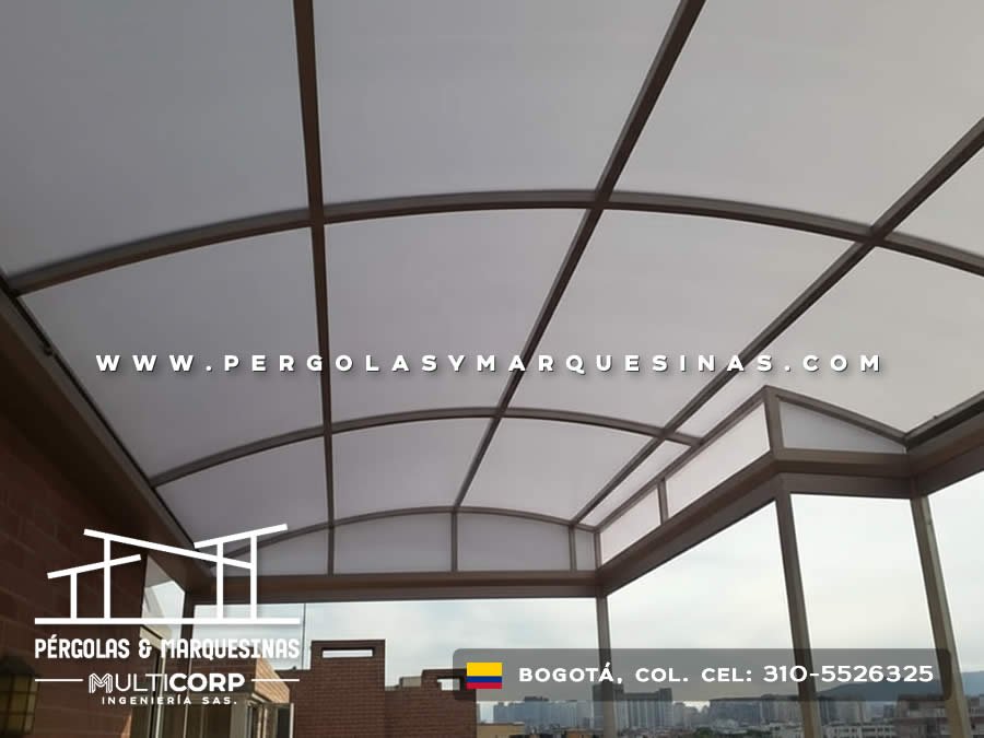 Cerramiento curvo en policarbonato con perfiles metálicos grises instalado en balcón de edificio en Bogotá, Colombia. Multicorp Ingeniería SAS.