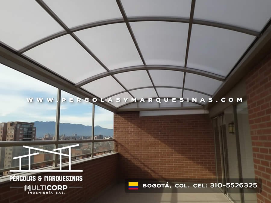 Marquesina curva con policarbonato translúcido y estructura gris en balcón con muro de ladrillo en Bogotá, Colombia. Multicorp Ingeniería SAS.