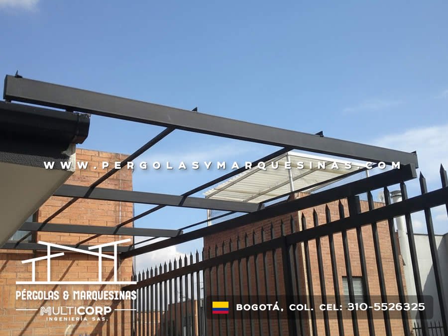 Marquesina metálica con techo de policarbonato translúcido instalada sobre portón vehicular en Bogotá, Colombia. Multicorp Ingeniería SAS.