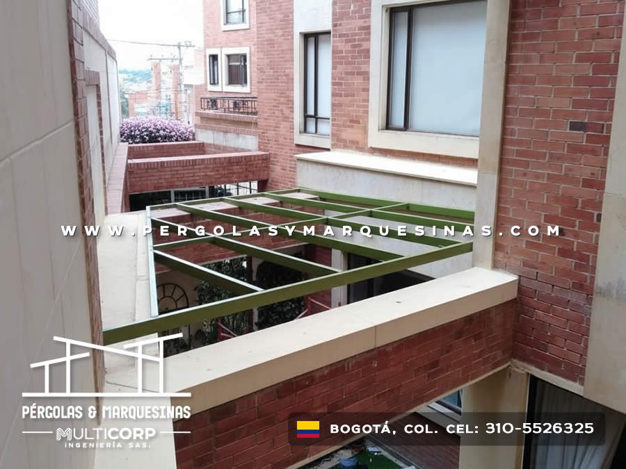 Pérgola metálica con vigas verdes en proceso de construcción en patio de edificio en Bogotá, Colombia. Multicorp Ingeniería SAS.