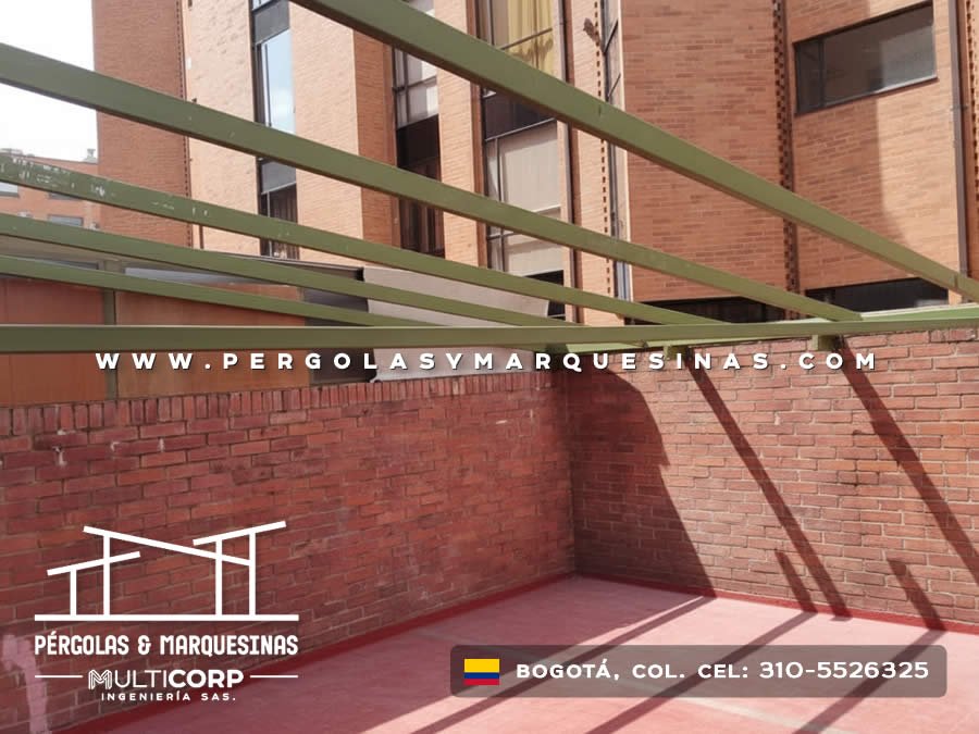Pérgola con vigas metálicas verdes sin cubierta en patio de edificio en Bogotá, Colombia. Multicorp Ingeniería SAS.