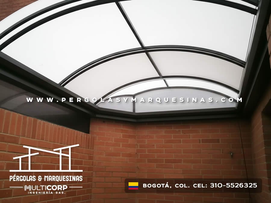 Marquesina curva en policarbonato sobre metal en entrada con pared de ladrillo en Bogotá, Colombia. Multicorp Ingeniería SAS. Marquesina curva en policarbonato sobre metal en entrada con pared de ladrillo en Bogotá, Colombia. Multicorp Ingeniería SAS.