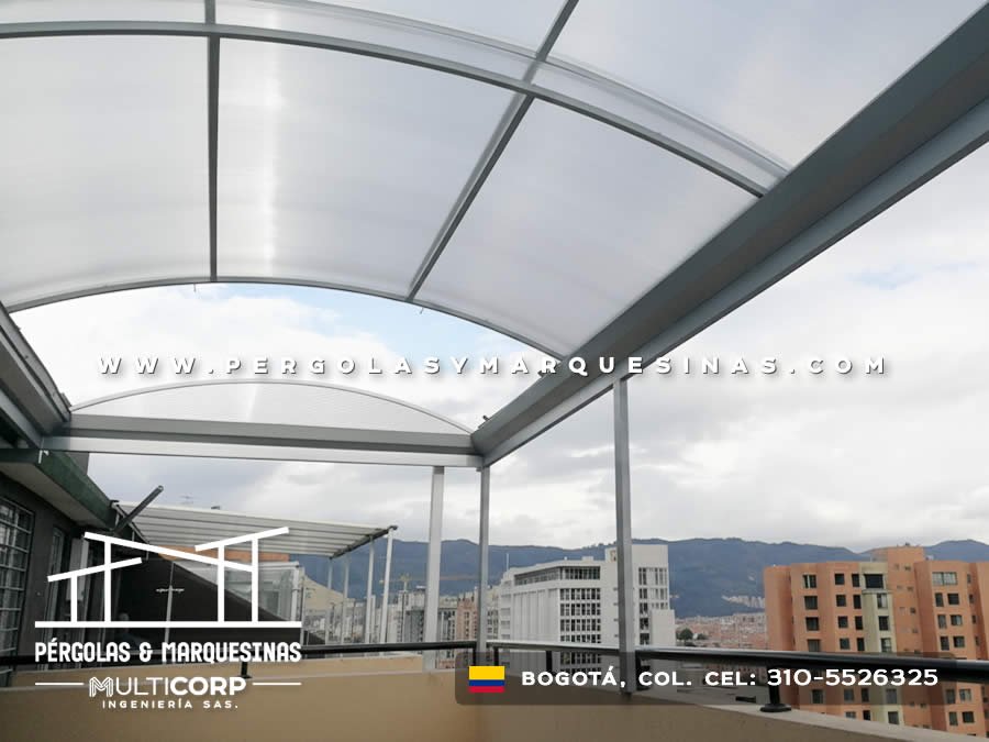 Pérgola curva en policarbonato sobre metal gris en azotea con vista panorámica en Bogotá, Colombia. Multicorp Ingeniería SAS. Pérgola curva en policarbonato sobre metal gris en azotea con vista panorámica en Bogotá, Colombia. Multicorp Ingeniería SAS.