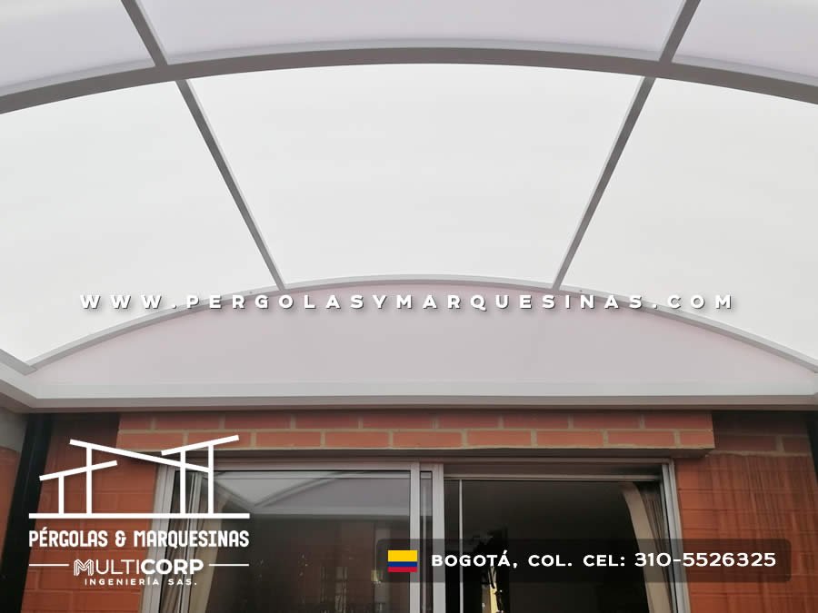Marquesina curva en policarbonato con marco gris sobre puerta de vidrio y ladrillo en Bogotá, Colombia. Multicorp Ingeniería SAS.