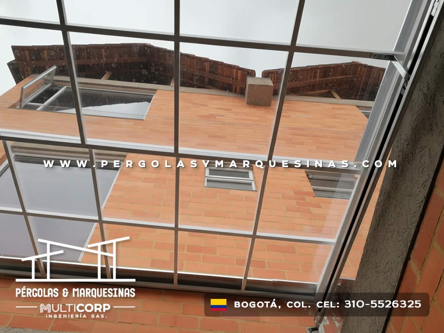 Cubierta modular transparente de policarbonato sobre patio residencial con vista a edificios en Bogotá, Colombia. Multicorp Ingeniería SAS.
