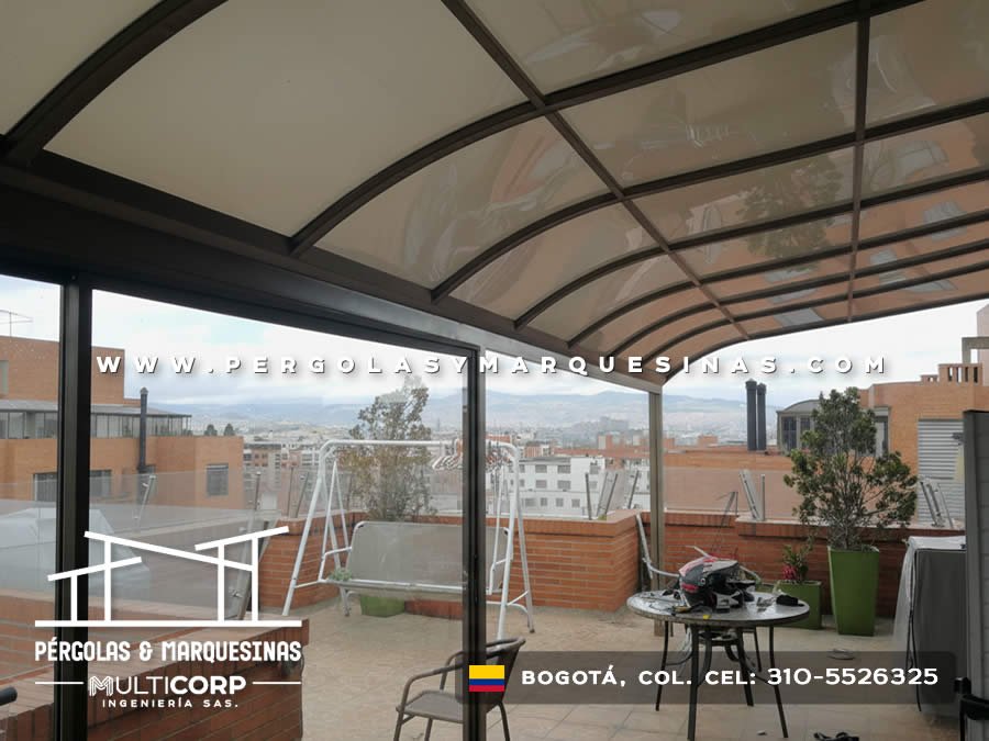 Pérgola curva de policarbonato con estructura metálica negra en terraza amoblada en Bogotá, Colombia. Multicorp Ingeniería SAS.