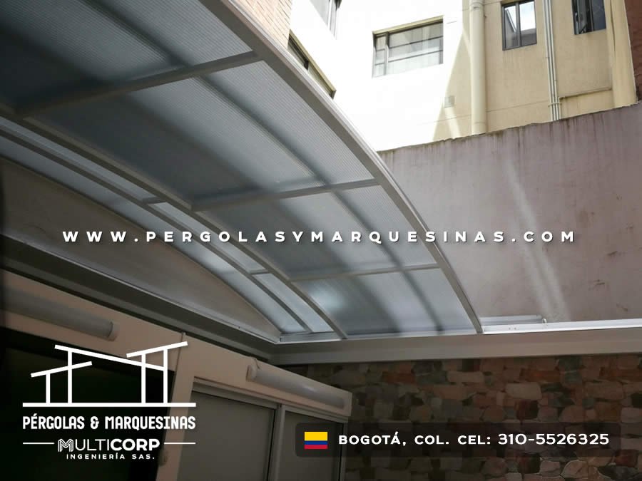 Marquesina curva de policarbonato con estructura metálica entre edificios residenciales en Bogotá, Colombia. Multicorp Ingeniería SAS.