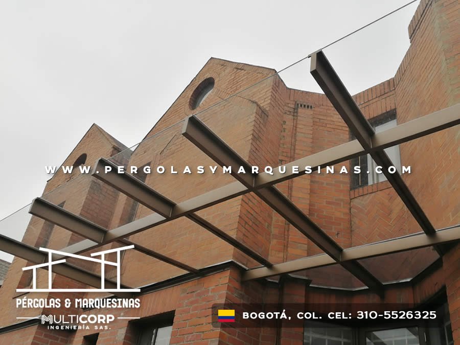Pérgola metálica con vigas de acero y techo translúcido sobre balcón con fachada de ladrillo en Bogotá, Colombia. Multicorp Ingeniería SAS.