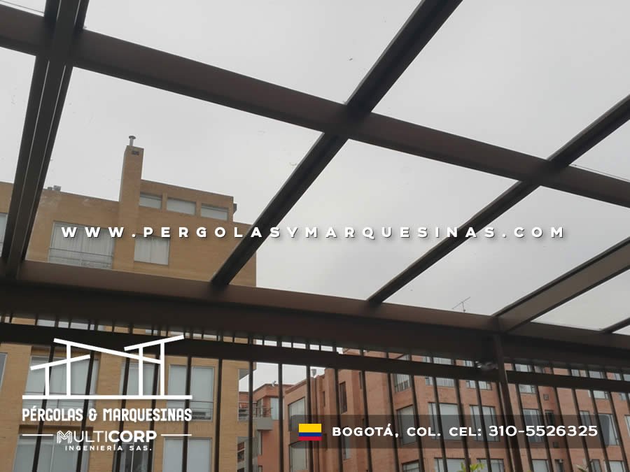 Pérgola de vidrio templado con estructura metálica negra sobre balcón con baranda en Bogotá, Colombia. Multicorp Ingeniería SAS.
