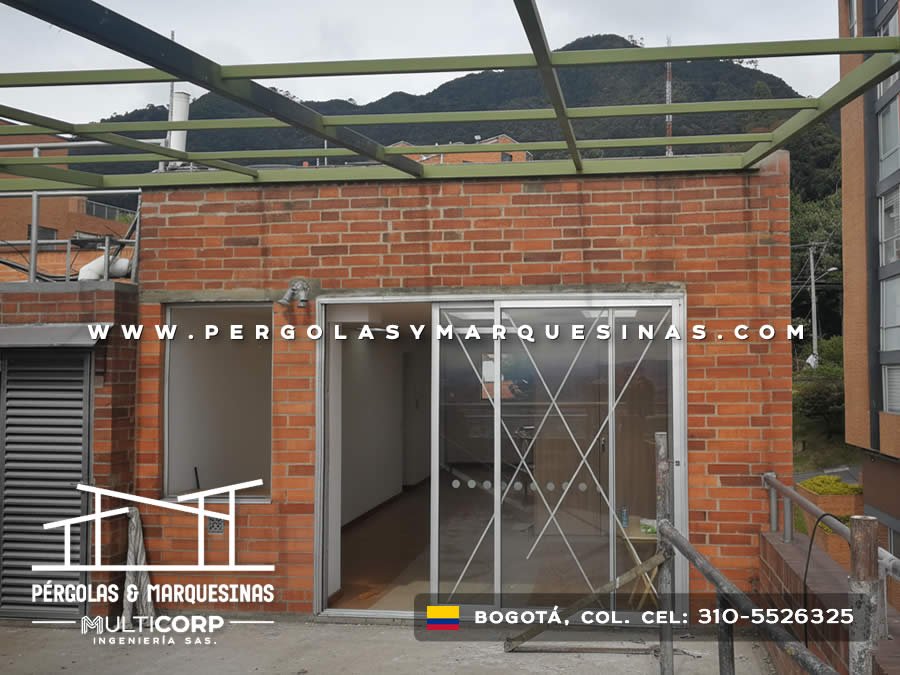 Estructura metálica de pérgola en construcción sobre terraza de ladrillo con vista a los cerros en Bogotá, Colombia. Multicorp Ingeniería SAS.