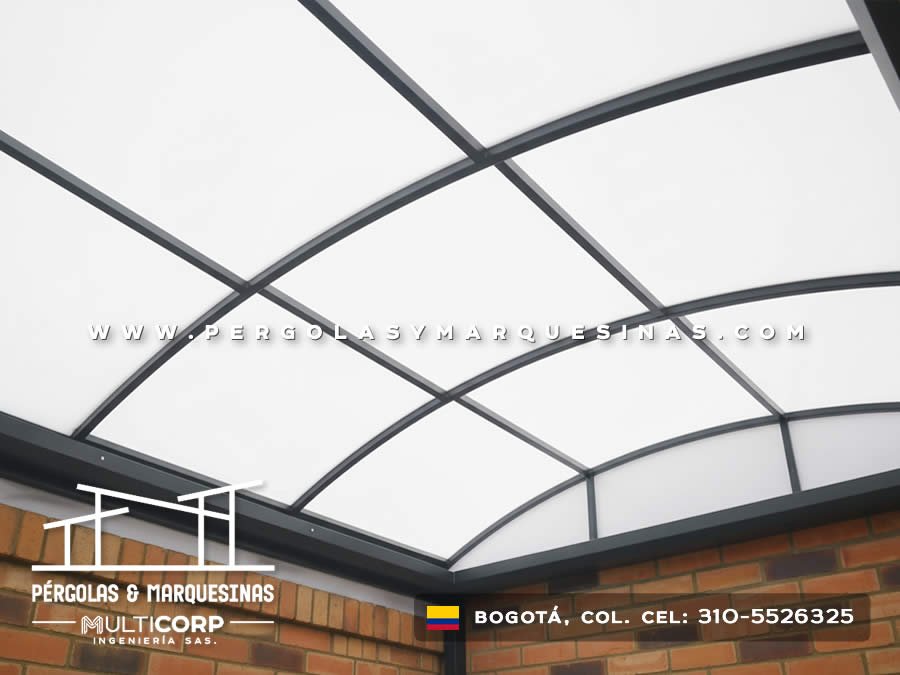 Cubierta curva de policarbonato translúcido con arcos metálicos sobre patio residencial en Bogotá, Colombia. Multicorp Ingeniería SAS.
