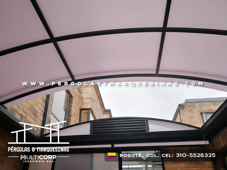 Cubierta curva de policarbonato con marco negro sobre entrada entre edificaciones en Bogotá, Colombia. Multicorp Ingeniería SAS.