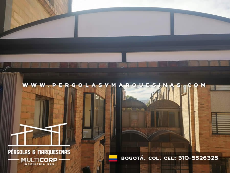 Cubierta curva de policarbonato con estructura negra entre edificaciones de ladrillo en Bogotá, Colombia. Multicorp Ingeniería SAS.