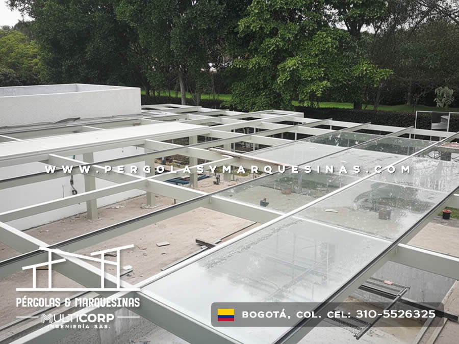 Pérgola de vidrio templado con estructura blanca en instalación sobre terraza con jardín en Bogotá, Colombia. Multicorp Ingeniería SAS.