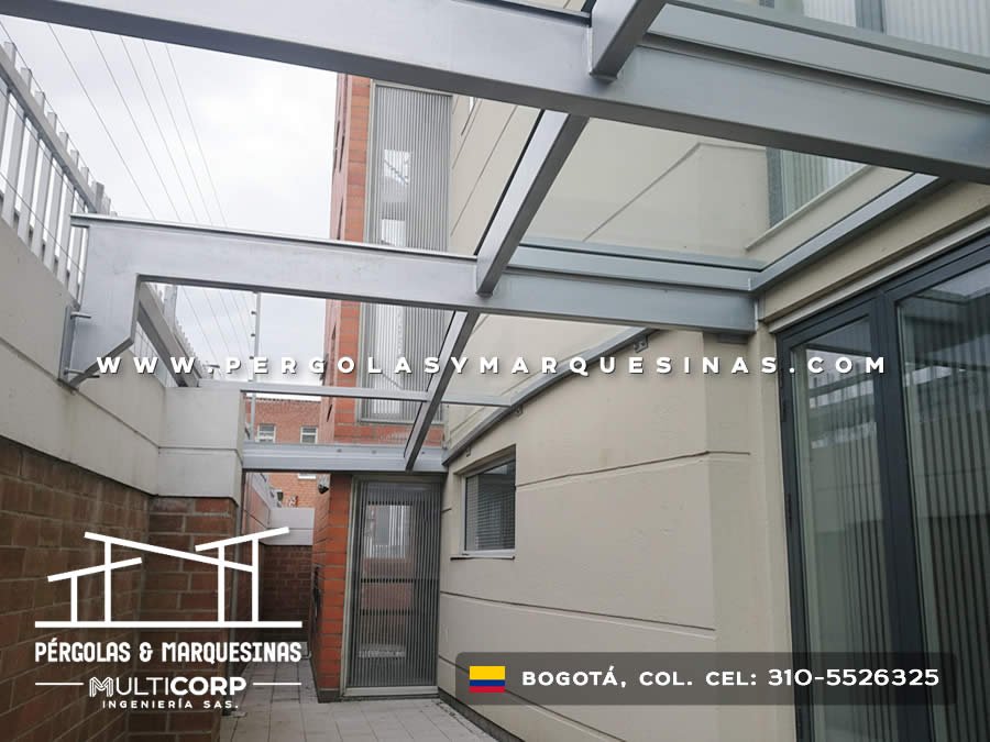 Pérgola de vidrio templado con marco metálico sobre patio entre edificaciones en Bogotá, Colombia. Multicorp Ingeniería SAS.