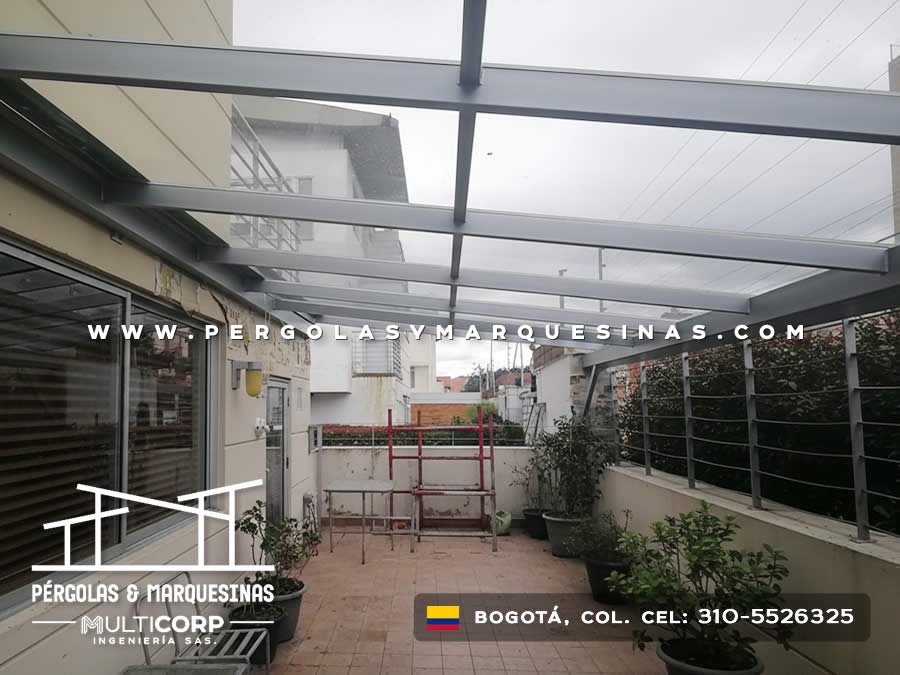 Pérgola de vidrio templado con estructura gris sobre terraza con plantas en Bogotá, Colombia. Multicorp Ingeniería SAS.