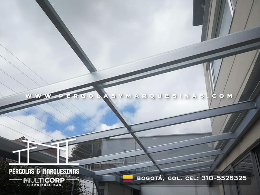 Techo de vidrio templado con estructura gris sobre patio entre fachadas modernas en Bogotá, Colombia. Multicorp Ingeniería SAS.