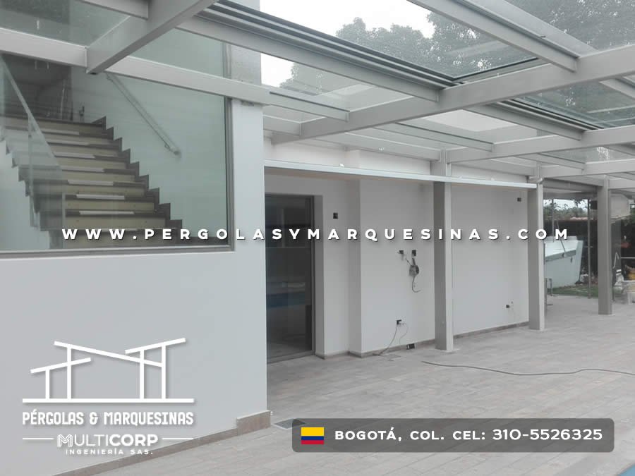 Pérgola de vidrio con marco metálico gris sobre terraza con escalera en vivienda moderna en Bogotá, Colombia. Multicorp Ingeniería SAS.