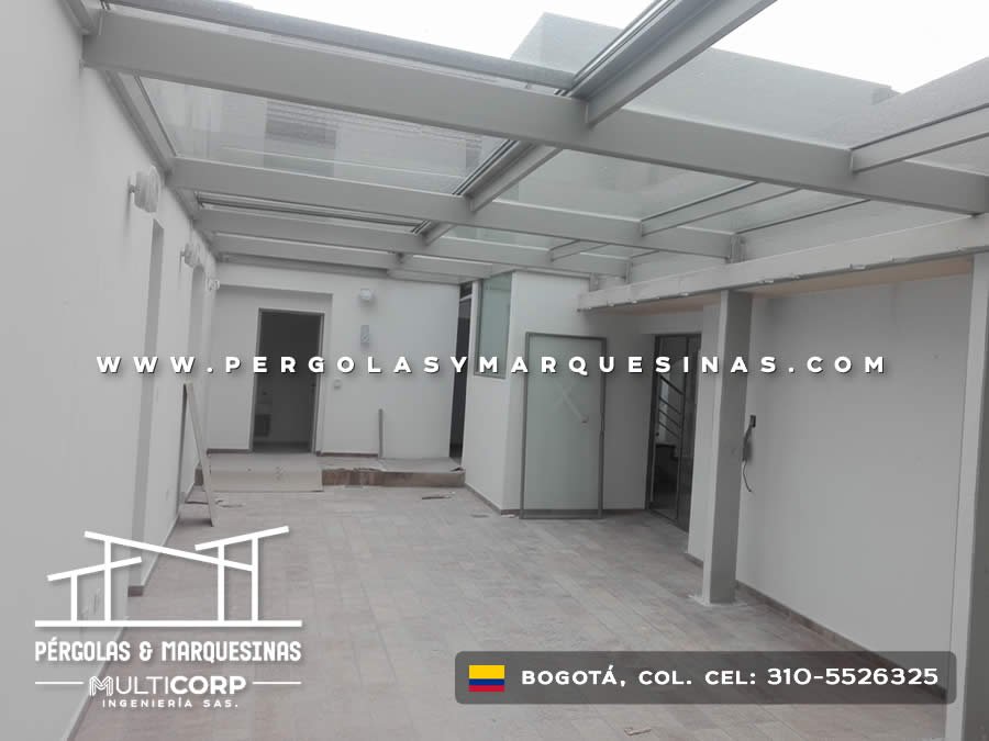 Cubierta transparente modular con vigas metálicas sobre patio en obra residencial con acabados blancos en Bogotá, Colombia. Multicorp Ingeniería SAS.