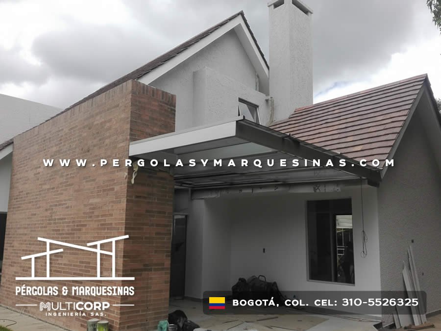 Cubierta metálica oscura sobre acceso principal en vivienda moderna con ladrillo y estuco gris en Bogotá, Colombia. Multicorp Ingeniería SAS.