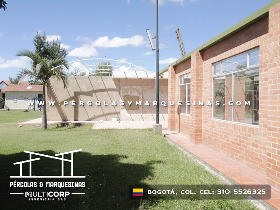 Estructura curva metálica blanca en construcción sobre muro de concreto con jardín residencial de Bogotá, Colombia. Multicorp Ingeniería SAS. Estructura curva metálica blanca en construcción sobre muro de concreto con jardín residencial de Bogotá, Colombia. Multicorp Ingeniería SAS.