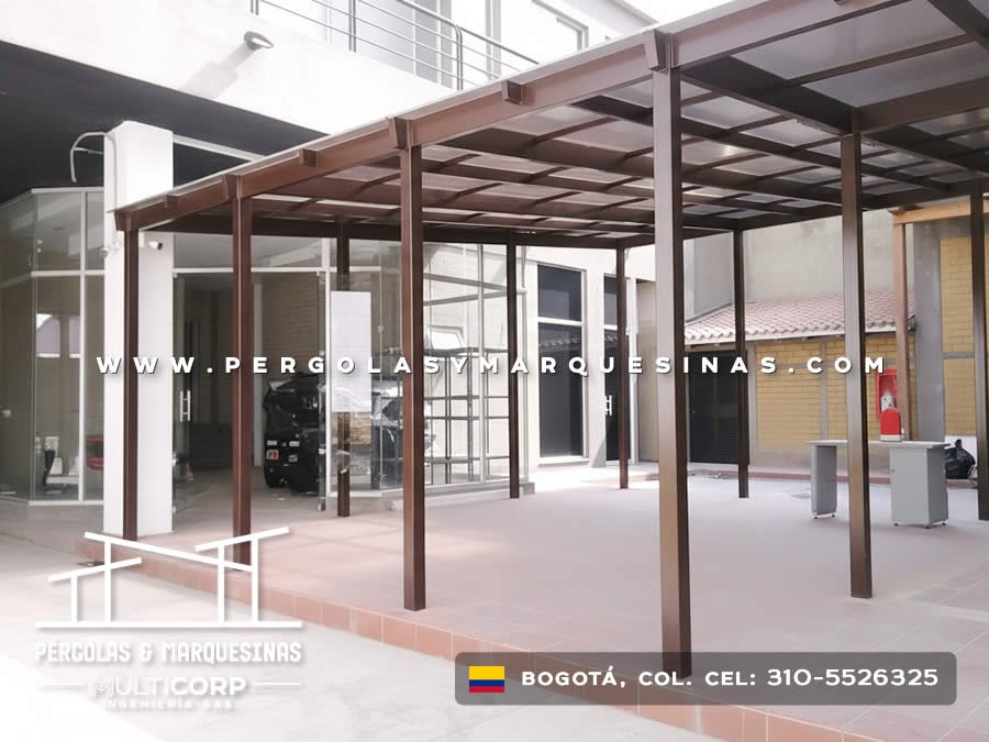 Pergola de metal color café con vigas horizontales en acceso principal de edificio moderno en Bogotá, Colombia. Multicorp Ingeniería SAS. Pergola de metal color café con vigas horizontales en acceso principal de edificio moderno en Bogotá, Colombia. Multicorp Ingeniería SAS.