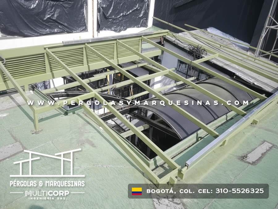 Estructura retráctil verde en proceso de fabricación sobre azotea con vista urbana de Bogotá, Colombia. Multicorp Ingeniería SAS. Estructura retráctil verde en proceso de fabricación sobre azotea con vista urbana de Bogotá, Colombia. Multicorp Ingeniería SAS.