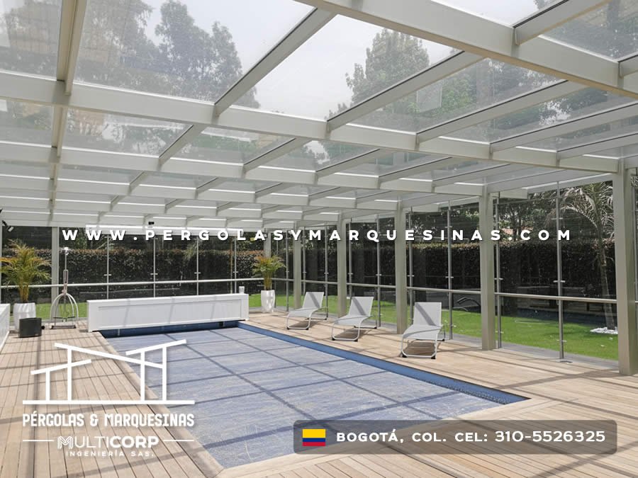 Techo de cristal con estructura metálica blanca sobre piscina con área lounge en jardín de Bogotá, Colombia. Multicorp Ingeniería SAS. Techo de cristal con estructura metálica blanca sobre piscina con área lounge en jardín de Bogotá, Colombia. Multicorp Ingeniería SAS.