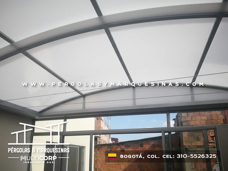 Techo de policarbonato con vigas metálicas grises sobre terraza urbana con vista a edificios en Bogotá, Colombia. Multicorp Ingeniería SAS. Techo de policarbonato con vigas metálicas grises sobre terraza urbana con vista a edificios en Bogotá, Colombia. Multicorp Ingeniería SAS.