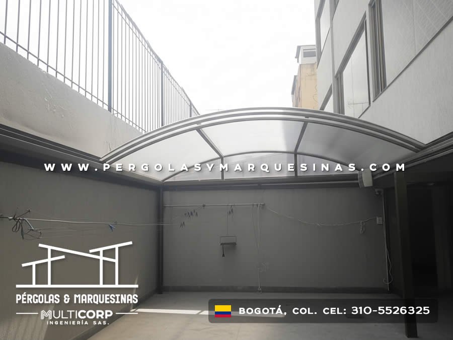 Cubierta arqueada de policarbonato con marco metálico gris sobre patio lateral de edificio en Bogotá, Colombia. Multicorp Ingeniería SAS. Cubierta arqueada de policarbonato con marco metálico gris sobre patio lateral de edificio en Bogotá, Colombia. Multicorp Ingeniería SAS.