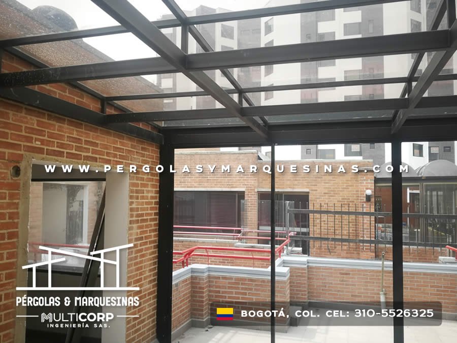 Estructura de vidrio templado con vigas metálicas negras sobre terraza en construcción con muro de ladrillo en Bogotá, Colombia. Multicorp Ingeniería SAS. Estructura de vidrio templado con vigas metálicas negras sobre terraza en construcción con muro de ladrillo en Bogotá, Colombia. Multicorp Ingeniería SAS.