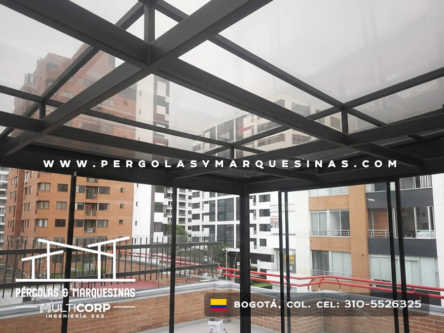 Cubierta de vidrio con estructura metálica negra sobre terraza con vista a edificios en Bogotá, Colombia. Multicorp Ingeniería SAS. Cubierta de vidrio con estructura metálica negra sobre terraza con vista a edificios en Bogotá, Colombia. Multicorp Ingeniería SAS.