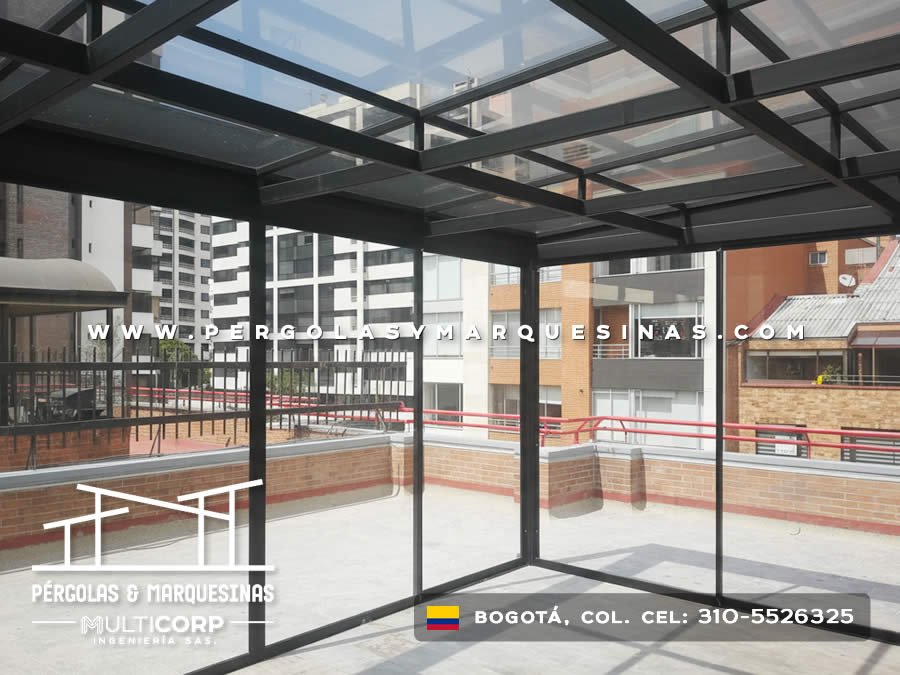 Pergola de vidrio templado y acero negro con techo parcialmente cubierto sobre terraza de edificio en Bogotá, Colombia. Multicorp Ingeniería SAS. Pergola de vidrio templado y acero negro con techo parcialmente cubierto sobre terraza de edificio en Bogotá, Colombia. Multicorp Ingeniería SAS.