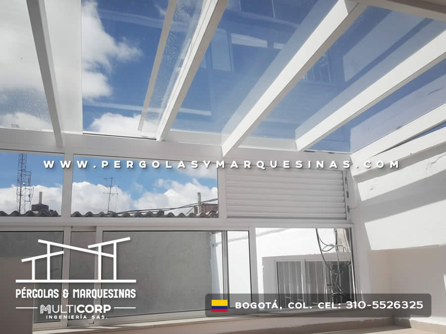 Cerramiento de vidrio con techo transparente y vigas blancas sobre terraza residencial con cortina enrollable en Bogotá, Colombia. Multicorp Ingeniería SAS. Cerramiento de vidrio con techo transparente y vigas blancas sobre terraza residencial con cortina enrollable en Bogotá, Colombia. Multicorp Ingeniería SAS.