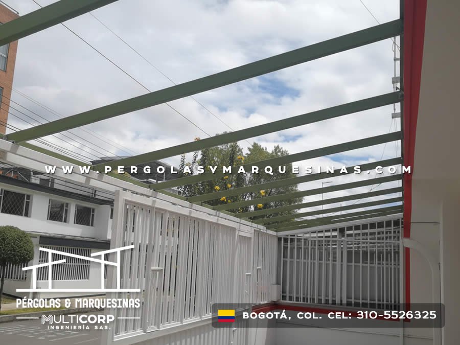 Pergola metalica con vigas verdes sobre terraza con listones verticales blancos en edificio residencial en Bogotá, Colombia. Multicorp Ingeniería SAS. Pergola metalica con vigas verdes sobre terraza con listones verticales blancos en edificio residencial en Bogotá, Colombia. Multicorp Ingeniería SAS.
