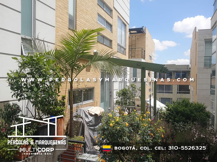 Pergola metalica verde con estructura abierta sobre terraza jardin con plantas y edificios modernos en Bogotá, Colombia. Multicorp Ingeniería SAS. Pergola metalica verde con estructura abierta sobre terraza jardin con plantas y edificios modernos en Bogotá, Colombia. Multicorp Ingeniería SAS.