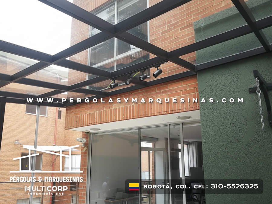 Pergola acristalada metalica negra con techo vidrio templado sobre edificio ladrillo rojo con focos en Bogotá, Colombia. Multicorp Ingeniería SAS. Pergola acristalada metalica negra con techo vidrio templado sobre edificio ladrillo rojo con focos en Bogotá, Colombia. Multicorp Ingeniería SAS.