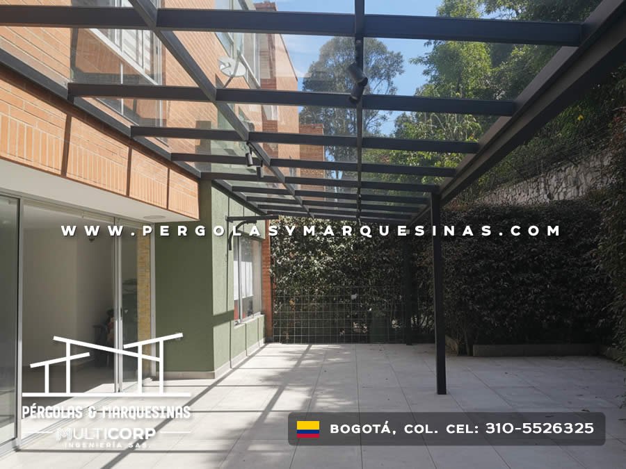 Pergola acristalada metalica negra techo vidrio transparente sobre terraza piso adoquinado con vegetal muro en Bogotá, Colombia. Multicorp Ingeniería SAS. Pergola acristalada metalica negra techo vidrio transparente sobre terraza piso adoquinado con vegetal muro en Bogotá, Colombia. Multicorp Ingeniería SAS.