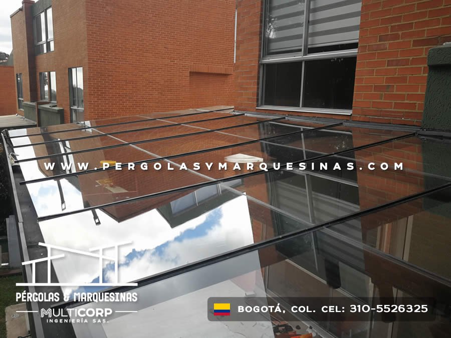 Pergola acristalada metalica negra techo vidrio templado sobre patio edificio ladrillo rojo con pared verde en Bogotá, Colombia. Multicorp Ingeniería SAS. Pergola acristalada metalica negra techo vidrio templado sobre patio edificio ladrillo rojo con pared verde en Bogotá, Colombia. Multicorp Ingeniería SAS.