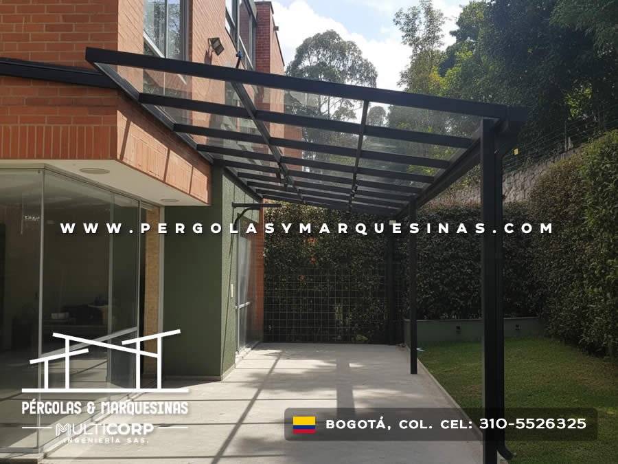 Pergola metalica negra techo policarbonato transparente sobre jardin cesped edificio ladrillo rojo con muro vegetal en Bogotá, Colombia. Multicorp Ingeniería SAS. Pergola metalica negra techo policarbonato transparente sobre jardin cesped edificio ladrillo rojo con muro vegetal en Bogotá, Colombia. Multicorp Ingeniería SAS.