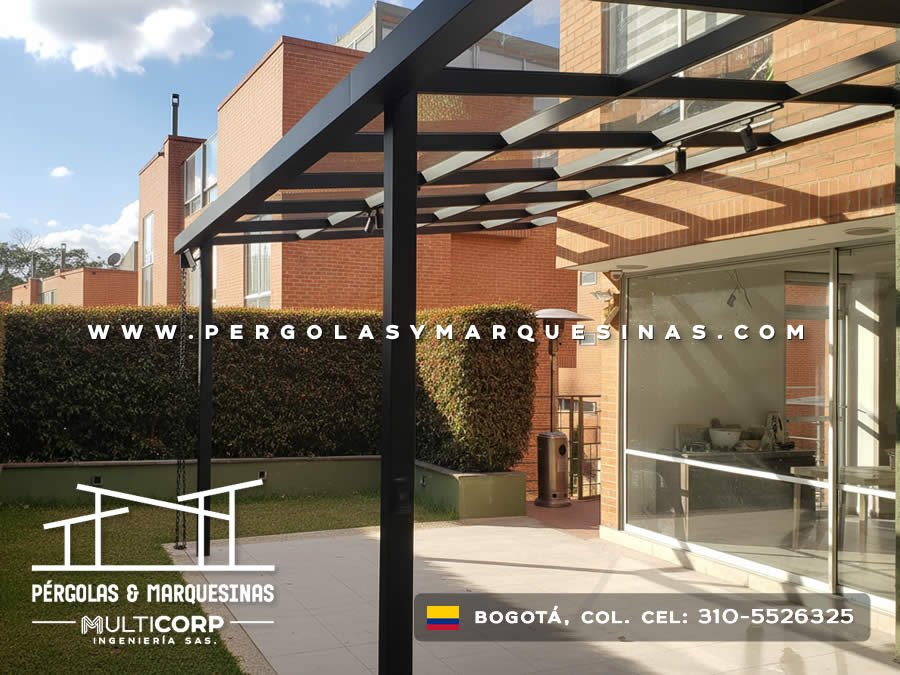 Pergola metalica negra estructura abierta con lamas sobre terraza jardin edificio ladrillo rojo con cesped en Bogotá, Colombia. Multicorp Ingeniería SAS. Pergola metalica negra estructura abierta con lamas sobre terraza jardin edificio ladrillo rojo con cesped en Bogotá, Colombia. Multicorp Ingeniería SAS.
