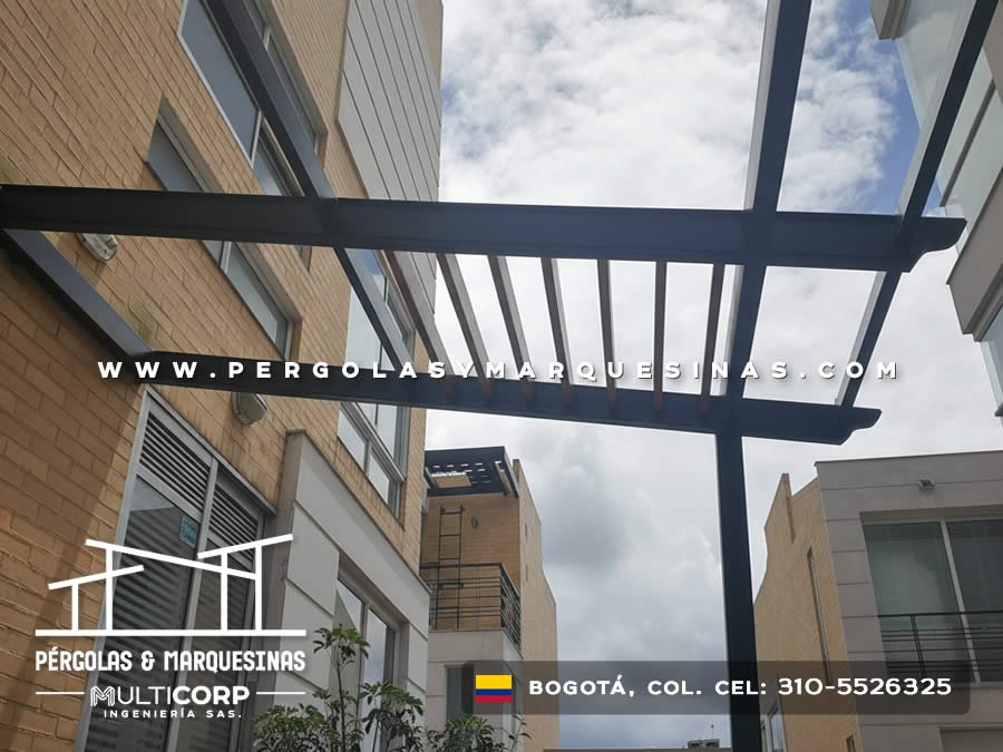Pergola metalica negra estructura abierta con lamas entre edificios residenciales urbanos con cielo nublado en Bogotá, Colombia. Multicorp Ingeniería SAS. Pergola metalica negra estructura abierta con lamas entre edificios residenciales urbanos con cielo nublado en Bogotá, Colombia. Multicorp Ingeniería SAS.