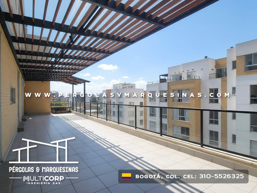 Pergola metalica negra con lamas de madera sobre terraza balcon edificio ladrillo con baranda y edificios urbanos en Bogotá, Colombia. Multicorp Ingeniería SAS. Pergola metalica negra con lamas de madera sobre terraza balcon edificio ladrillo con baranda y edificios urbanos en Bogotá, Colombia. Multicorp Ingeniería SAS.