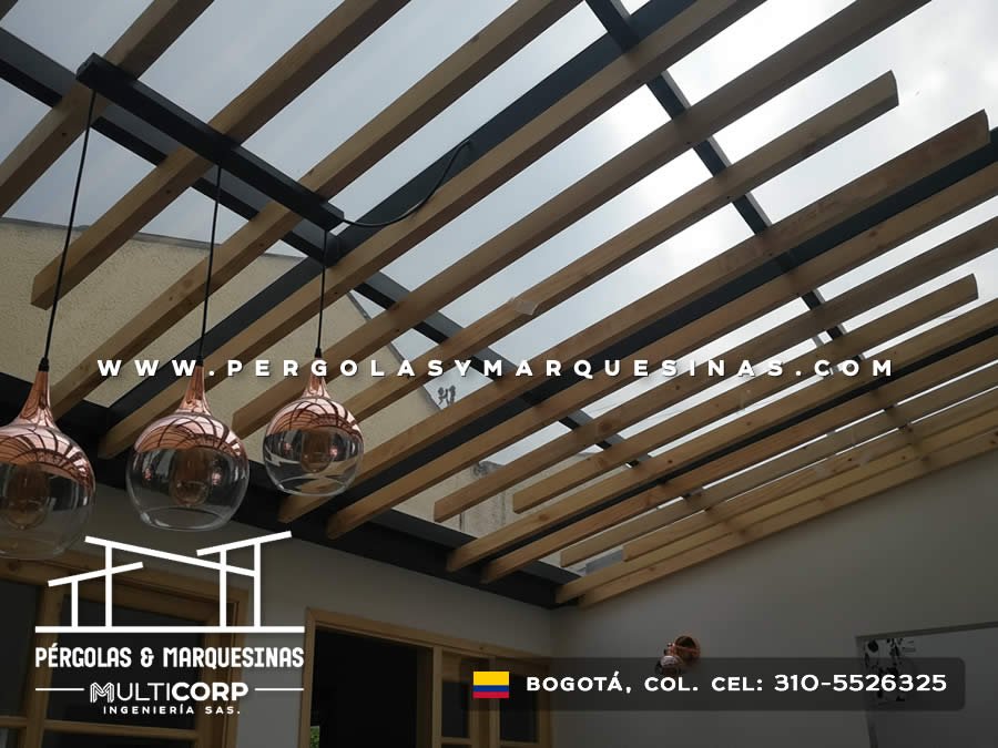 Pergola metalica negra con lamas de madera sobre espacio interior con focos colgantes decorativos en Bogotá, Colombia. Multicorp Ingeniería SAS. Pergola metalica negra con lamas de madera sobre espacio interior con focos colgantes decorativos en Bogotá, Colombia. Multicorp Ingeniería SAS.
