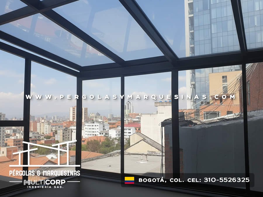 Pergola acristalada cerrada metalica negra con vidrio y ventanas sobre terraza alta con panorama urbano en Bogotá, Colombia. Multicorp Ingeniería SAS. Pergola acristalada cerrada metalica negra con vidrio y ventanas sobre terraza alta con panorama urbano en Bogotá, Colombia. Multicorp Ingeniería SAS.