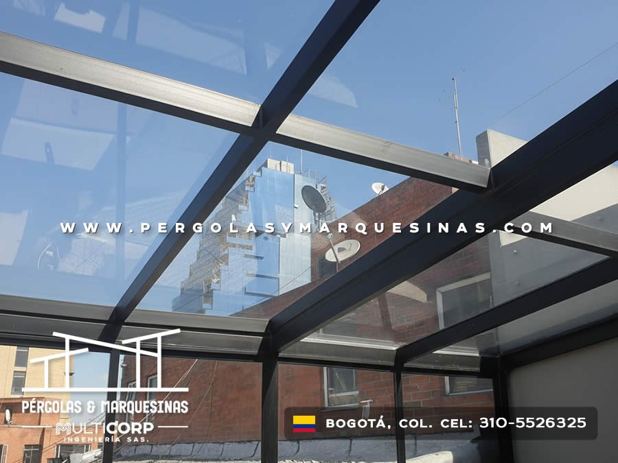 Pergola acristalada metalica negra techo vidrio sobre terraza edificio ladrillo con antenas y edificios urbanos en Bogotá, Colombia. Multicorp Ingeniería SAS. Pergola acristalada metalica negra techo vidrio sobre terraza edificio ladrillo con antenas y edificios urbanos en Bogotá, Colombia. Multicorp Ingeniería SAS.