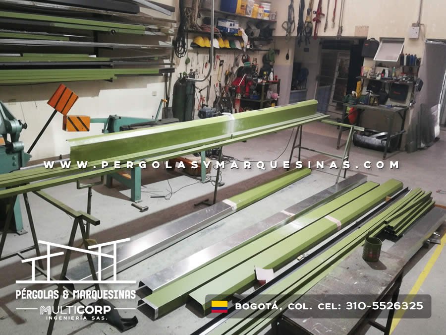 Fabricacion en taller de perfiles metalicos verdes largos sobre mesas de trabajo con herramientas en Bogotá, Colombia. Multicorp Ingeniería SAS. Fabricacion en taller de perfiles metalicos verdes largos sobre mesas de trabajo con herramientas en Bogotá, Colombia. Multicorp Ingeniería SAS.