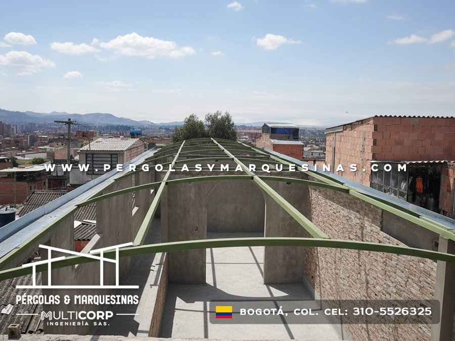 Estructura curva metalica verde sobre azotea edificio ladrillo con panorama urbano y montanas en Bogotá, Colombia. Multicorp Ingeniería SAS. Estructura curva metalica verde sobre azotea edificio ladrillo con panorama urbano y montanas en Bogotá, Colombia. Multicorp Ingeniería SAS.